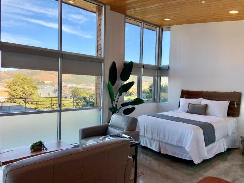 ein Schlafzimmer mit einem Bett, einem Sofa und Fenstern in der Unterkunft Anchor Inn Pacifica in Pacifica