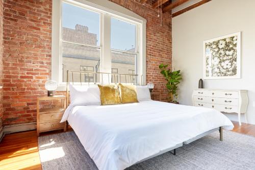 1 dormitorio con cama blanca y pared de ladrillo en Sonder The Drayton, en Savannah