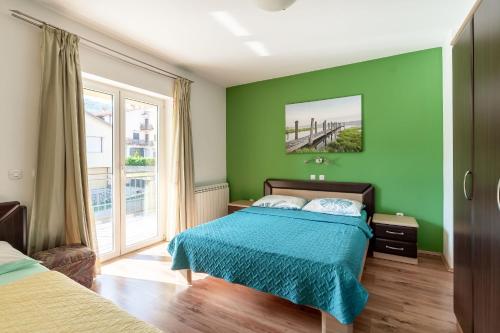 Apartments Sime في ماتولي: غرفة نوم بجدران خضراء وسرير بمفرش ازق