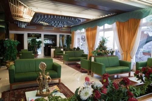 a lobby with green couches and flowers in a building at Hotel Villa Mulino ***S in Garda