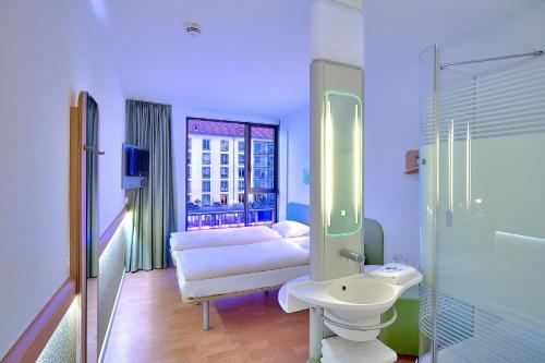 uma casa de banho com uma cama, um lavatório e um espelho. em ibis budget Dresden City em Dresden