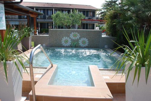 a large swimming pool in a yard with plants at Residence La Margherita in Lazise