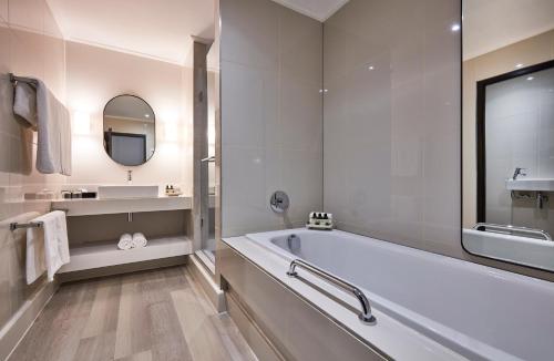 
a bathroom with a tub, sink, mirror and bathtub at Victoria & Alfred Hotel in Cape Town
