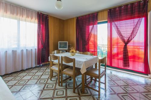 comedor con mesa, sillas y cortinas rojas en Apartments Bilaja, en Marina
