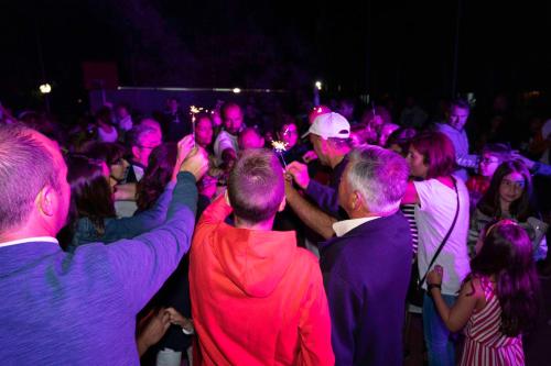 Un groupe de personnes debout dans une foule avec des lumières colorées dans l'établissement Camping Baltar, à Portonovo