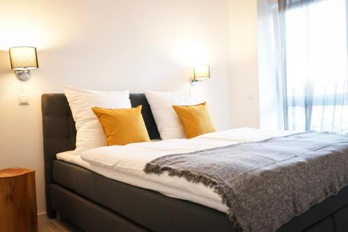 - un lit avec des oreillers jaunes et blancs et une fenêtre dans l'établissement Prime Park Deluxe Apartment Aschaffenburg, à Aschaffenbourg