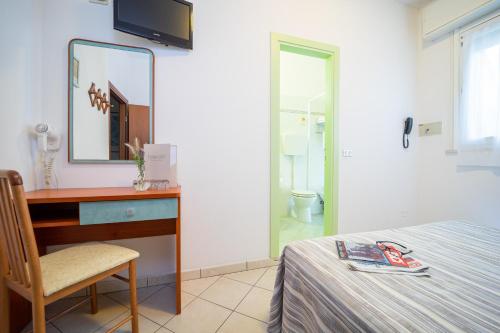 a bedroom with a bed and a desk and a mirror at Hotel Abc in Cervia