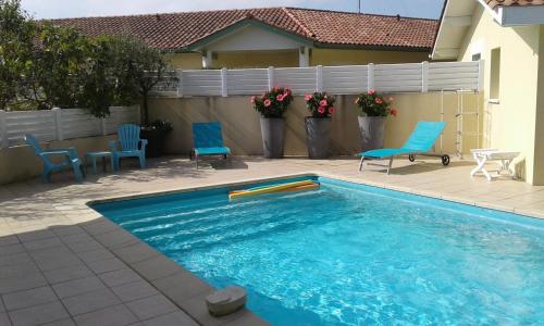 a swimming pool with blue chairs and a fence at T2 Tarnos avec piscine in Labenne