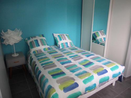 a bedroom with a bed with a colorful comforter at T2 Tarnos avec piscine in Labenne