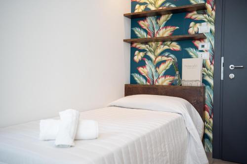 a bedroom with a white bed with a tropical wallpaper at Hotel Abc in Cervia