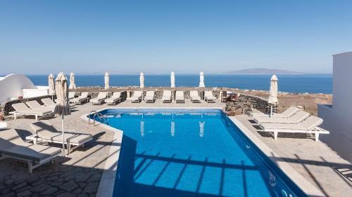 a swimming pool with chairs and the ocean in the background at Agnadi View Villa in Oia