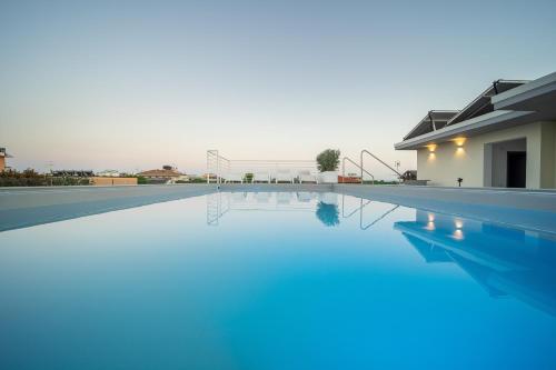 a swimming pool with blue water in front of a house at Hotel Abc in Cervia
