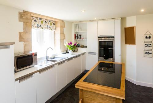 a kitchen with white cabinets and a wooden counter top at The Tower in Thorpeness