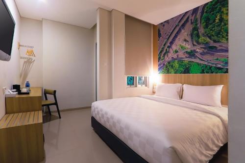 a bedroom with a large white bed and a desk at Cordela Inn Bengkulu in Bengkulu