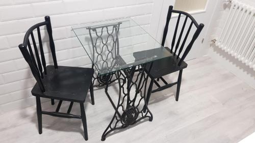 a glass table and two black chairs in a room at 1930 Diecinueve Treinta "Diseño, historia y confort en el centro de Gijón" in Gijón