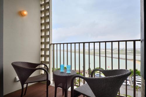 a balcony with two chairs and a table with two candles at Senagajima Island Resort & Spa in Tomigusuku