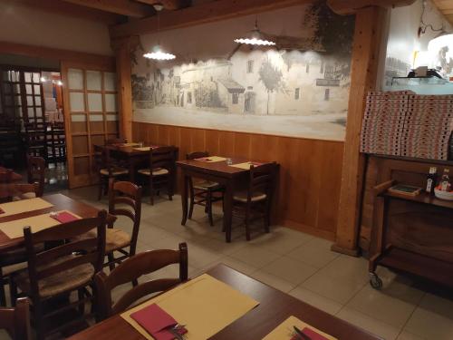 Albergo Baschera في فاغاغنا: مطعم بطاولات وكراسي خشبية وجدار جداري