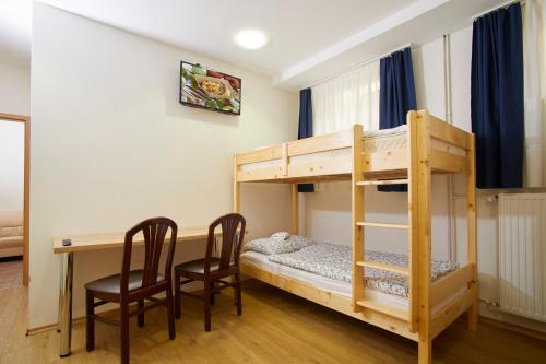 a room with a bunk bed and a desk and chairs at Hostel Delalut in Ravne na Koroškem