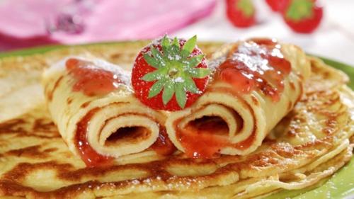 een bord pannenkoeken met een aardbei erop bij Gulabi Bagh Resort in Jaipur