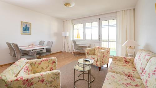 ein Wohnzimmer mit einem Sofa, Stühlen und einem Tisch in der Unterkunft Werzer Strandcasino Hotel in Pörtschach am Wörthersee