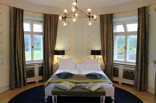 1 dormitorio con 1 cama con lámpara de araña y ventanas en Schloss Höhenried en Bernried