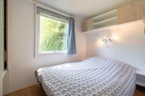 1 dormitorio con cama y ventana en Camping Le Parc des Monges en Auribeau-sur-Siagne