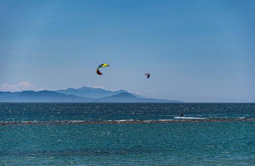 two people are flying kites in the ocean at Golfo del Sole Hotel & Holiday Resort in Follonica