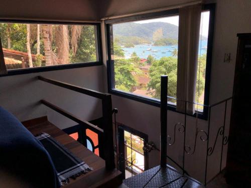 a room with two large windows and a view of a river at Bergamota in Abraão