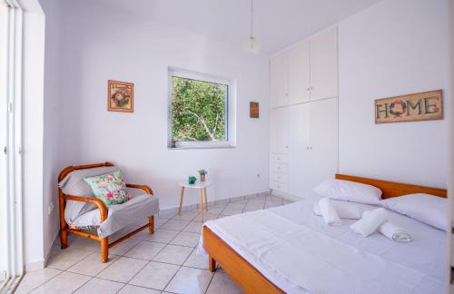 a white bedroom with a bed and a chair at Monolithi Seaside Cottage in Kanali
