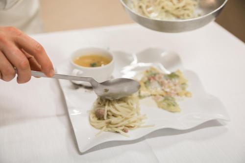 a person holding a spoon over a plate of pasta at Phi Hotel Dei Medaglioni in Correggio