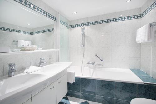 a white bathroom with a tub and a sink at Hotel Angela in Lech am Arlberg