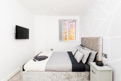 a white bedroom with a bed and a window at cozy stay in Birmingham by the Canal !! in Birmingham