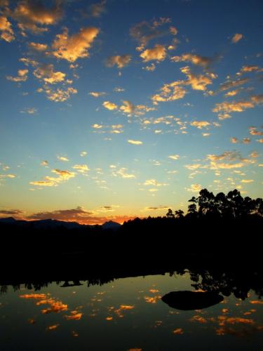 a sunset over a lake with trees in the background at Tenikwa Wildlife Centre & Spa in Plettenberg Bay