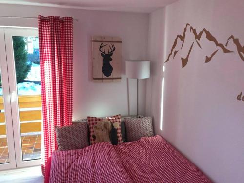 ein Schlafzimmer mit einem roten Bett mit einem Hirschbild an der Wand in der Unterkunft Almsternchen 2 - Almsternchen 3 in Oberstdorf