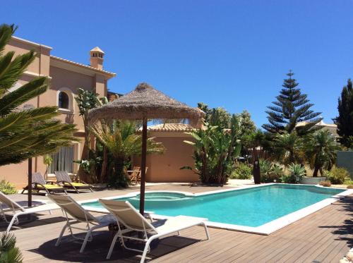 a villa with a swimming pool with chairs and an umbrella at Casa Canavial in Luz