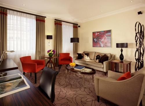 a living room with a couch and red chairs at Taj 51 Buckingham Gate Suites and Residences in London