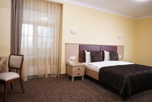 a bedroom with a bed and a chair and a window at GRAND OTRADA Hotel Resort & SPA in Odesa