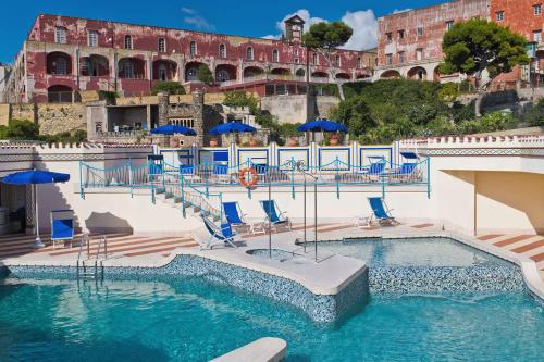 a swimming pool with chairs and umbrellas in front of a building at Hotel Royal Continental in Naples