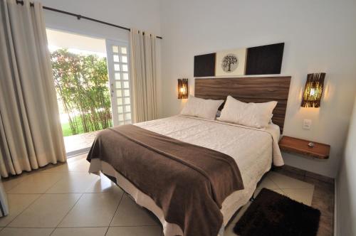 a bedroom with a large bed and a large window at Pousada Flores do Cerrado in Pirenópolis