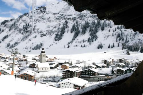 a town covered in snow in front of a mountain at Hotel Angela in Lech am Arlberg