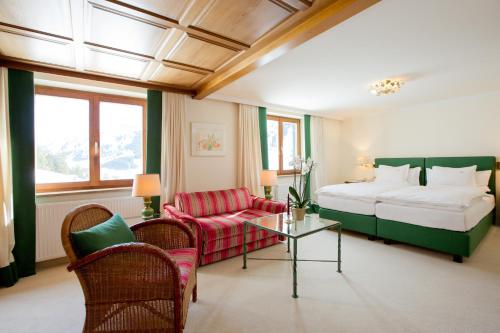 a hotel room with a bed and a couch and a table at Hotel Angela in Lech am Arlberg