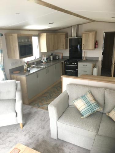 a living room with a couch and a kitchen at Bynack Lodge in Boat of Garten
