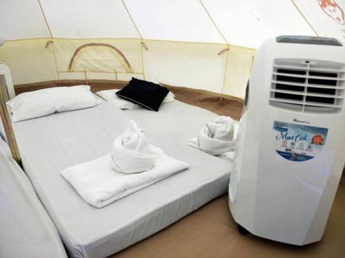 a bed in a tent with towels and a heater at Baan Rai Pu Fa in Sattahip