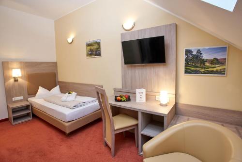 a hotel room with a bed and a desk and a television at Vulkanhotel balance&selfness ***S in Steffeln