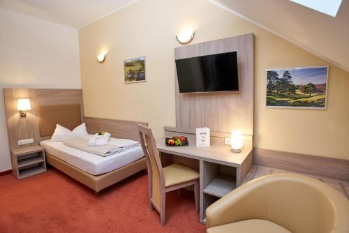 ein Hotelzimmer mit einem Bett, einem Schreibtisch und einem TV in der Unterkunft Vulkanhotel balance&selfness ***S in Steffeln