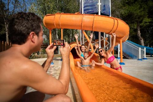 un hombre tomando una foto de un grupo de niños en una diapositiva en Tamarit Beach Resort, en Tamarit
