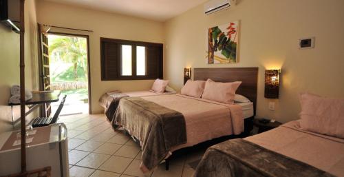 a hotel room with two beds and a window at Pousada Flores do Cerrado in Pirenópolis