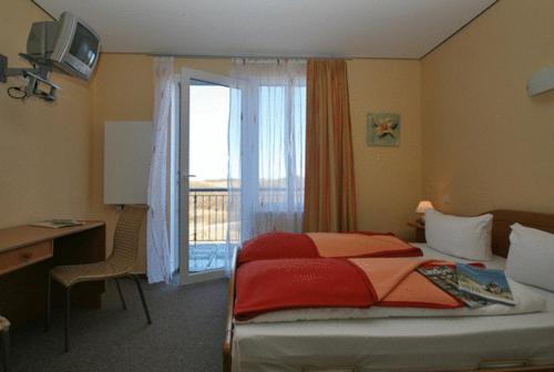 a bedroom with a bed and a desk and a window at Dünenhotel Borkum in Borkum