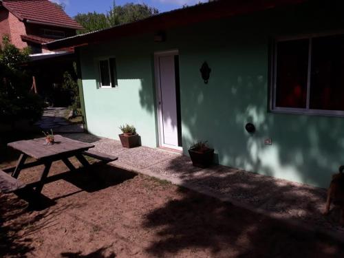 a picnic table in front of a house with a door at La casita de Pablo in Santa Teresita
