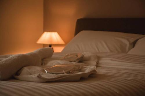 a robe laying on a bed next to a lamp at API Projects Nafplio - Family Superior Apartment in Nafplio